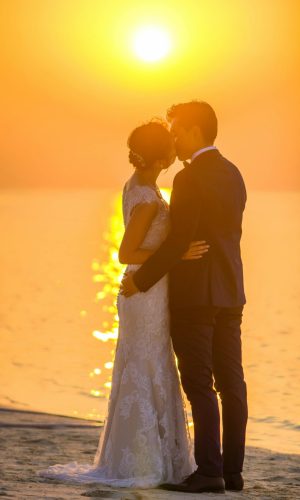 Maldives Captivating moment of a couple sharing a kiss during a beach sunset wedding, exuding romance.